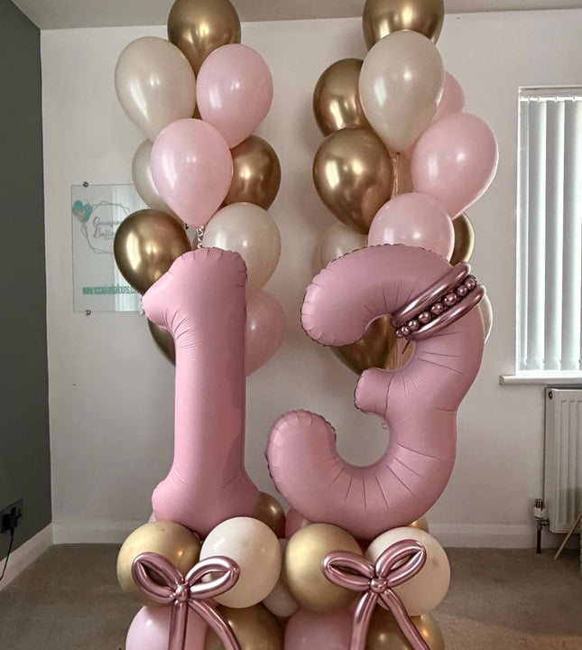 Pink number 13 balloons with personalised gold hearts, rose gold balloon bows, a pink, cream and gold base, and matching helium bouquets.