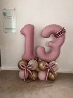 Pink number 13 balloons with personalised gold hearts, rose gold balloon bows, a pink, cream and gold base, and matching helium bouquets.