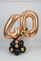 Gold 40 foil number balloons on a black and gold balloon base, finished with a black balloon band and a small gold balloon flower.