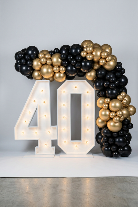 Illuminated 40 numbers framed by a black and metallic gold balloon garland across the top and down the right side.