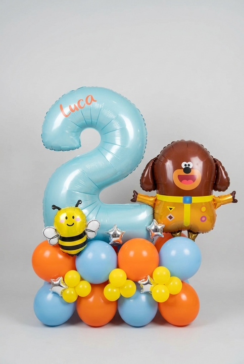 Blue number 2 balloon personalised with Luca, alongside Duggee and bee foil balloons on a blue, orange and yellow base with silver stars.