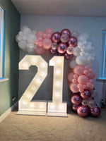 Light-up 21 numbers framed by a white, pink, metallic berry and confetti balloon garland across the top and down the right side.