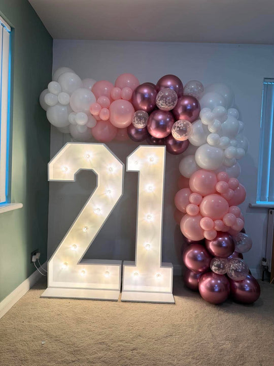 Light-up 21 numbers framed by a white, pink, metallic berry and confetti balloon garland across the top and down the right side.