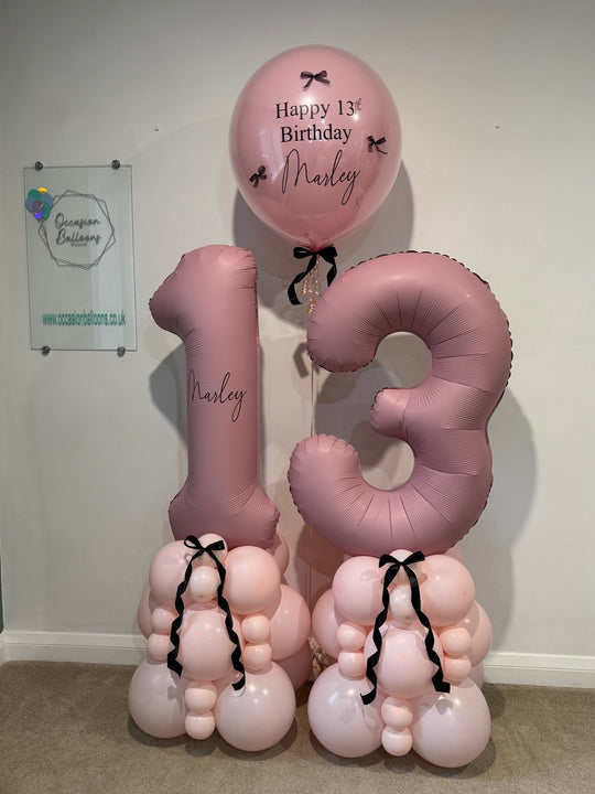 Dusky pink number 13 balloon towers with soft pink bases and black bows, accompanied by a personalised birthday bubble balloon for Marley.