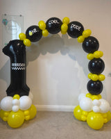 Black, yellow and white One Cool Dude first birthday balloon arch with a personalised black number 1 for Harrison and chequered detailing.