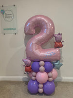 A custom balloon decoration featuring a large metallic pink number 2 balloon with the name 'Lettie' written on it, supported by a cluster of pink, purple, and lavender balloons, including Peppa Pig character balloons and a silver star balloon.
