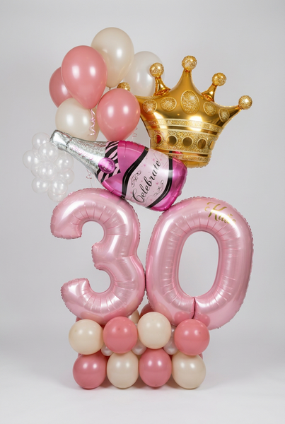 Pink number 30 balloon display with a pink and cream base, gold crown, champagne bottle foil balloon and coordinating helium balloons.