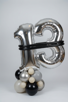 Silver number 13 balloons personalised with Joshua Kai, joined with black balloon bands on a black, grey, cream and metallic balloon base.