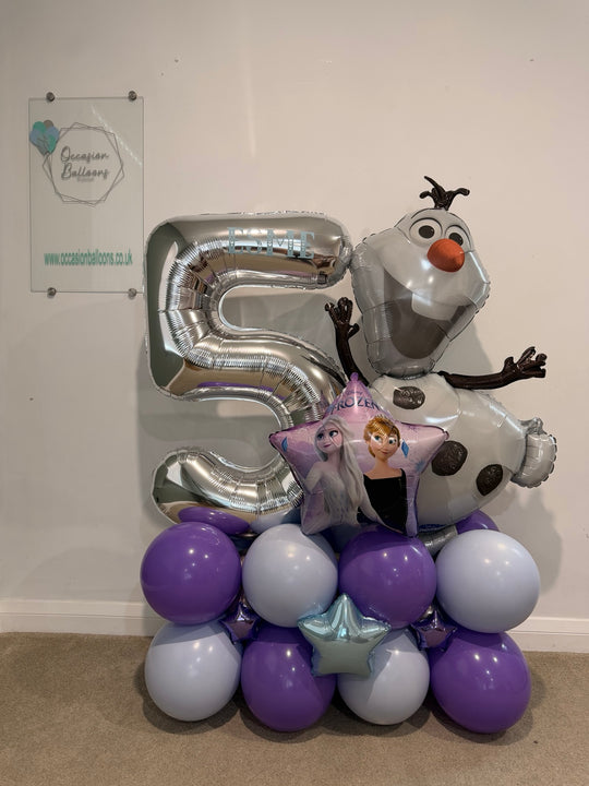 Silver number 5 balloon personalised with Esme, alongside Olaf and an Anna and Elsa star balloon, on a purple and pale blue base with foil stars.