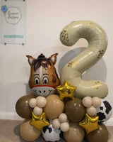 Personalised cream number 2 balloon beside a horse foil balloon, on a brown, beige, cream and cow-print base with gold stars.