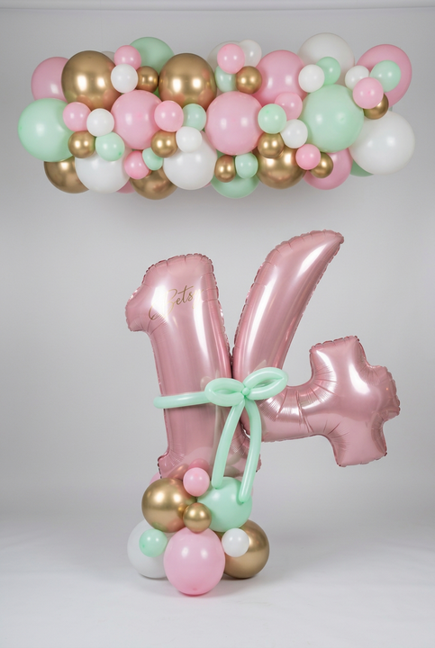 Personalised pink 14 balloons with a mint bow and pastel balloon base, beneath a matching pink, mint, white and gold balloon garland.