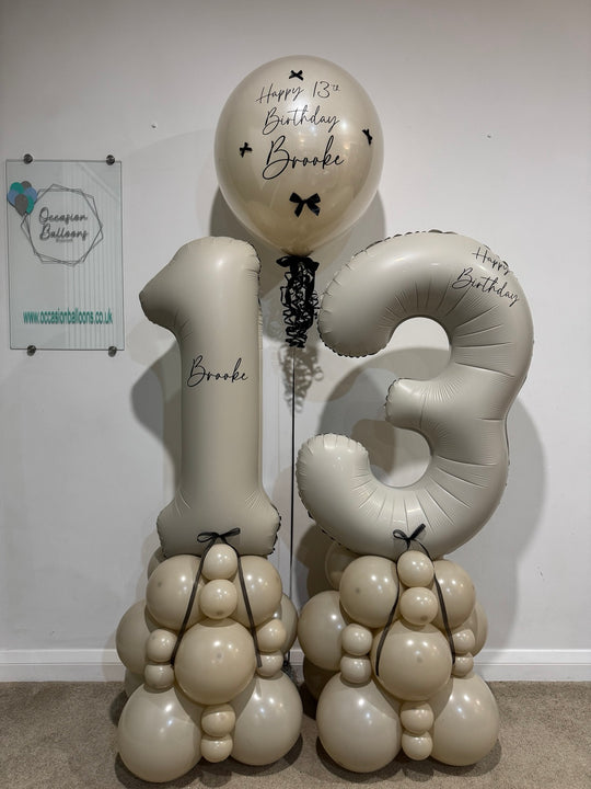 Cream number 13 balloon towers with champagne and cream bases, black bows and a personalised birthday bubble balloon for Brooke.