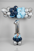 Silver number 1 balloon with a rocket on a blue and silver base, beneath a navy, light blue and silver garland with stars and balloon planet rings.