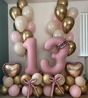 Pink number 13 balloons with personalised gold hearts, rose gold balloon bows, a pink, cream and gold base, and matching helium bouquets.