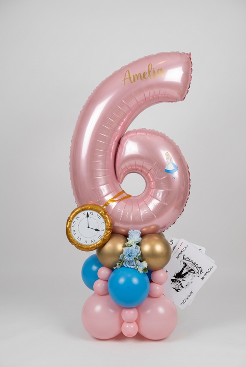 Pink number 6 balloon personalised with Amelia, featuring Alice in Wonderland details, a gold pocket watch, playing cards and a pink, blue and gold base.