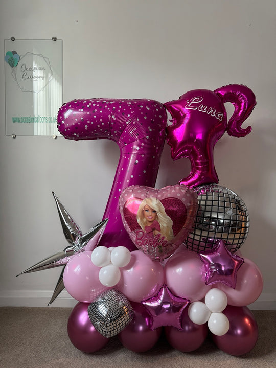 Pink Barbie number 7 balloon display personalised for Luna, with a Barbie heart, ponytail silhouette, silver disco balloons and metallic stars.