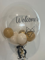 Clear bubble balloon with the Fox Aesthetics logo and Welcome wording, filled with gold and cream balloons and finished with matching ribbons.