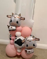 White number 1 balloon personalised with Mia-Mae in pink, with two cow foil balloons and a pink, white and cow-print balloon base.
